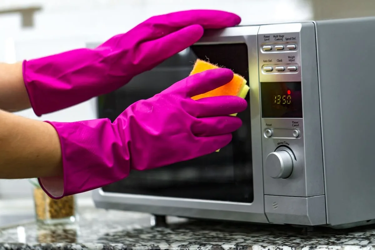 hands-rubber-gloves-cleaning-microwave-using-sponge