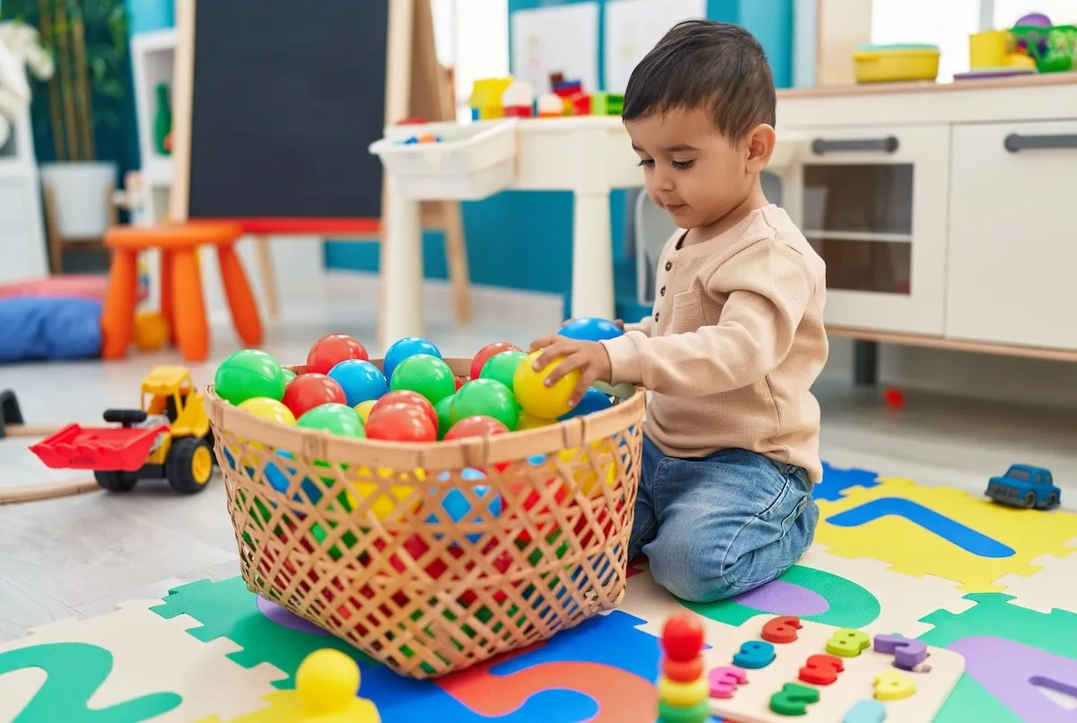 adorable-hispanic-toddler-playing-with-balls-sitting-floor-kindergarten (1)